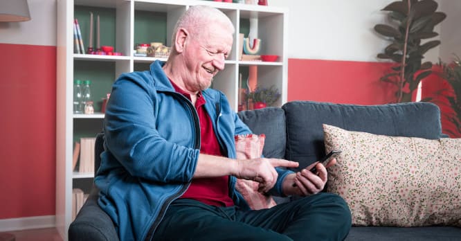 Persona mayor sonriente con un móvil en la mano