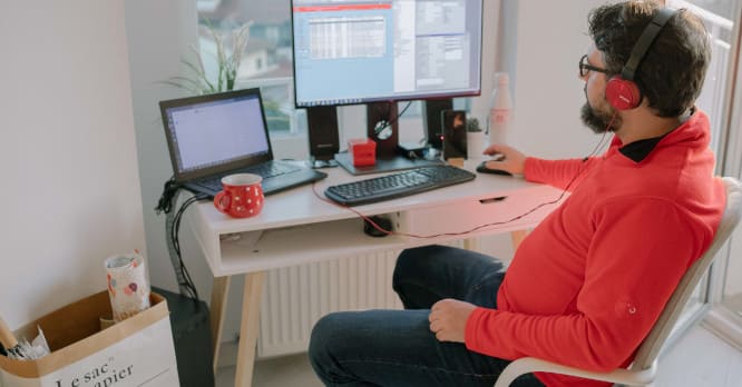 joven sentado en silla ergonómica delante de ordenador.