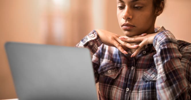 Persona observando con atención la pantalla de su portátil, representando la importancia de proteger la red WiFi del hogar para mantener la seguridad digital.