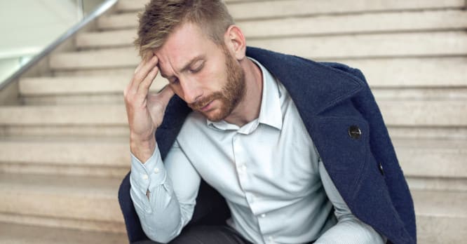 Persona con gesto de preocupación sentada en unas escaleras, simbolizando el estrés y la urgencia de actuar tras sufrir el robo de un móvil.