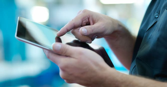 Primer plano de unas manos utilizando una tablet, representando la búsqueda y evaluación de dispositivos electrónicos para apostar por la tecnología sostenible.