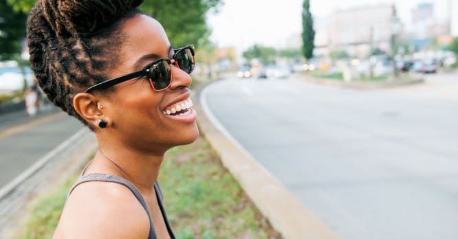 Mujer joven sonriendo feliz y relajada al aire libre, representando la paz mental y la libertad que se consigue al aplicar el minimalismo digital para limpiar nuestra vida online.
