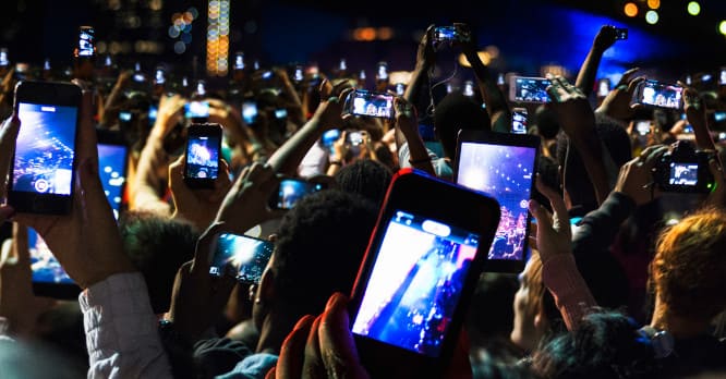 Multitud de personas grabando un concierto con las pantallas de sus teléfonos móviles, ilustrando la importancia de mantener una relación sana con la tecnología y cuidar el bienestar digital.